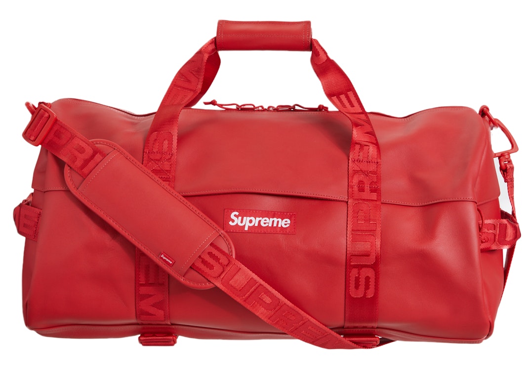 Person holding red and white Supreme leather duffel bag outdoor
